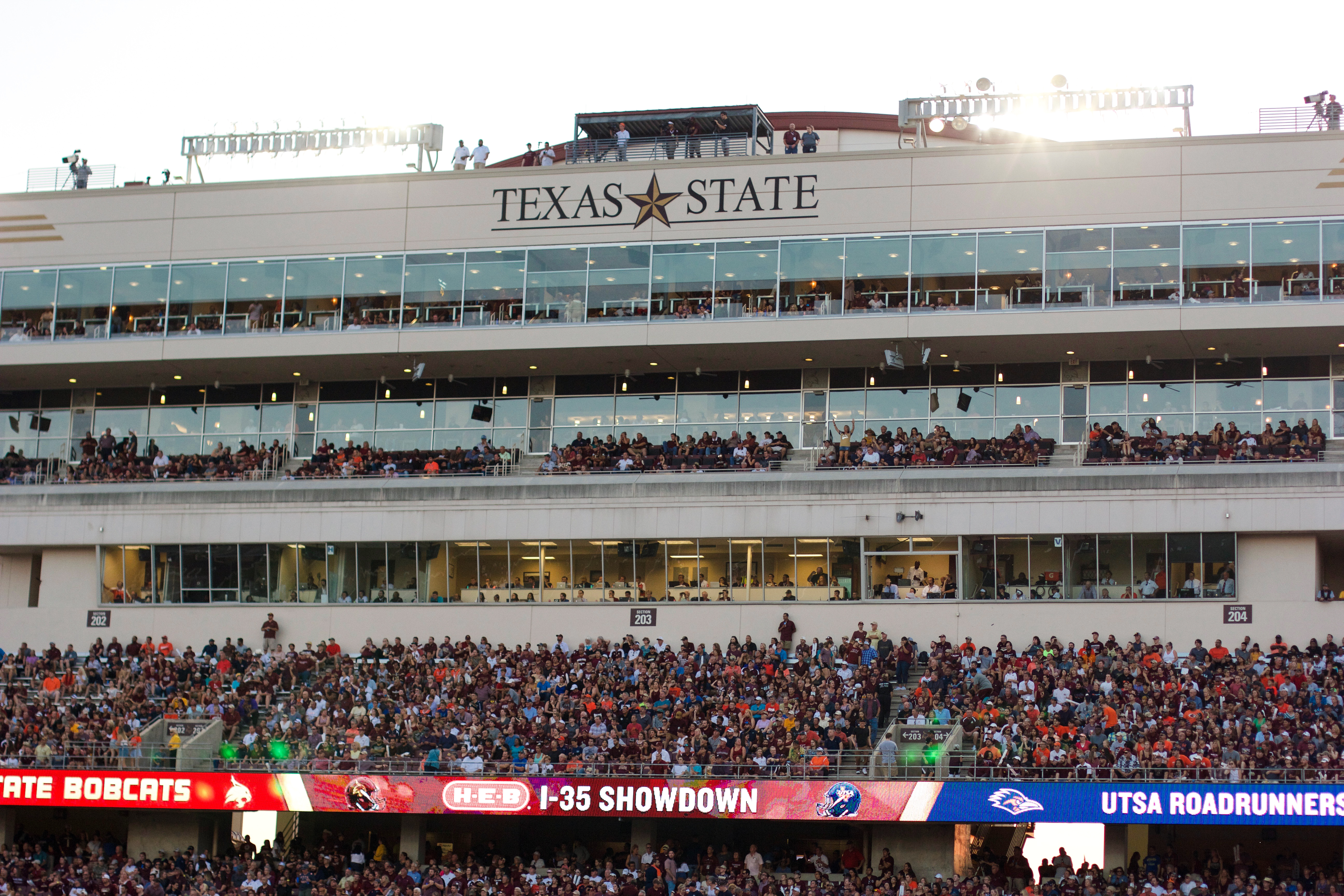 The sun sets behind the stands and press boxes of Bobcat Stadium.