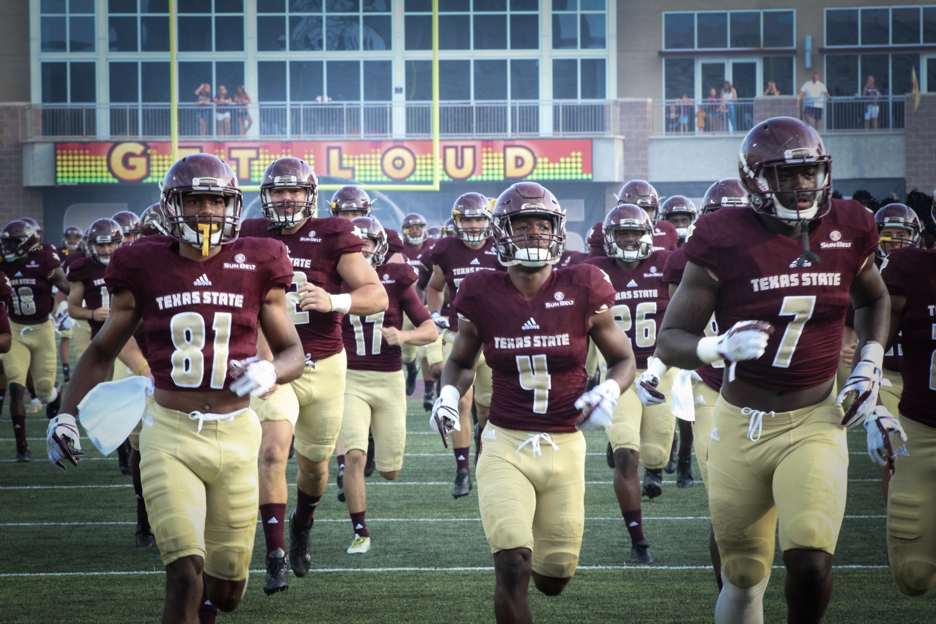 Texas State football players running onto field