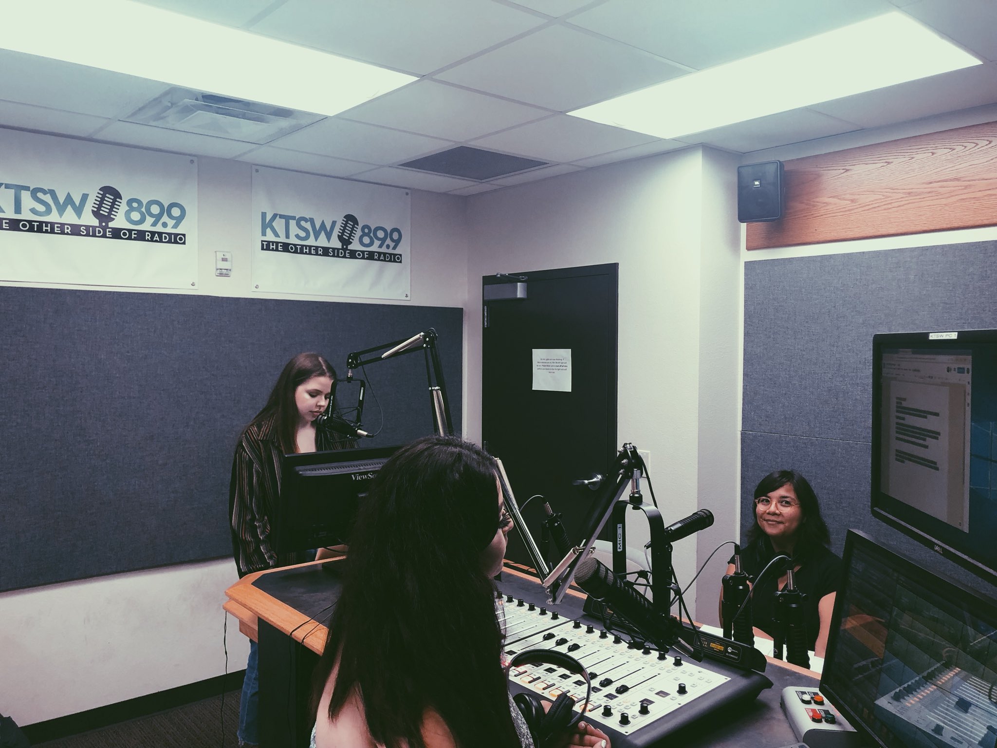 Three young women in the KTSW studio. One is smiling.