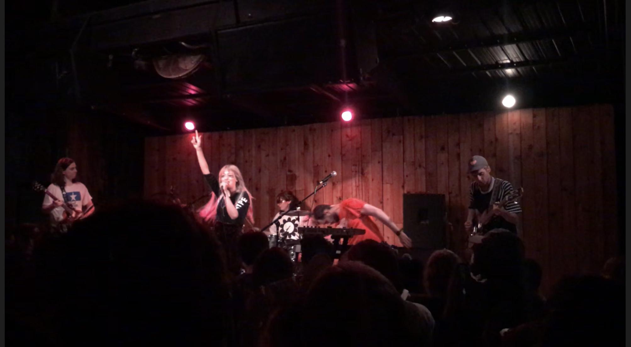 A blonde woman and a band performing a high-energy show.