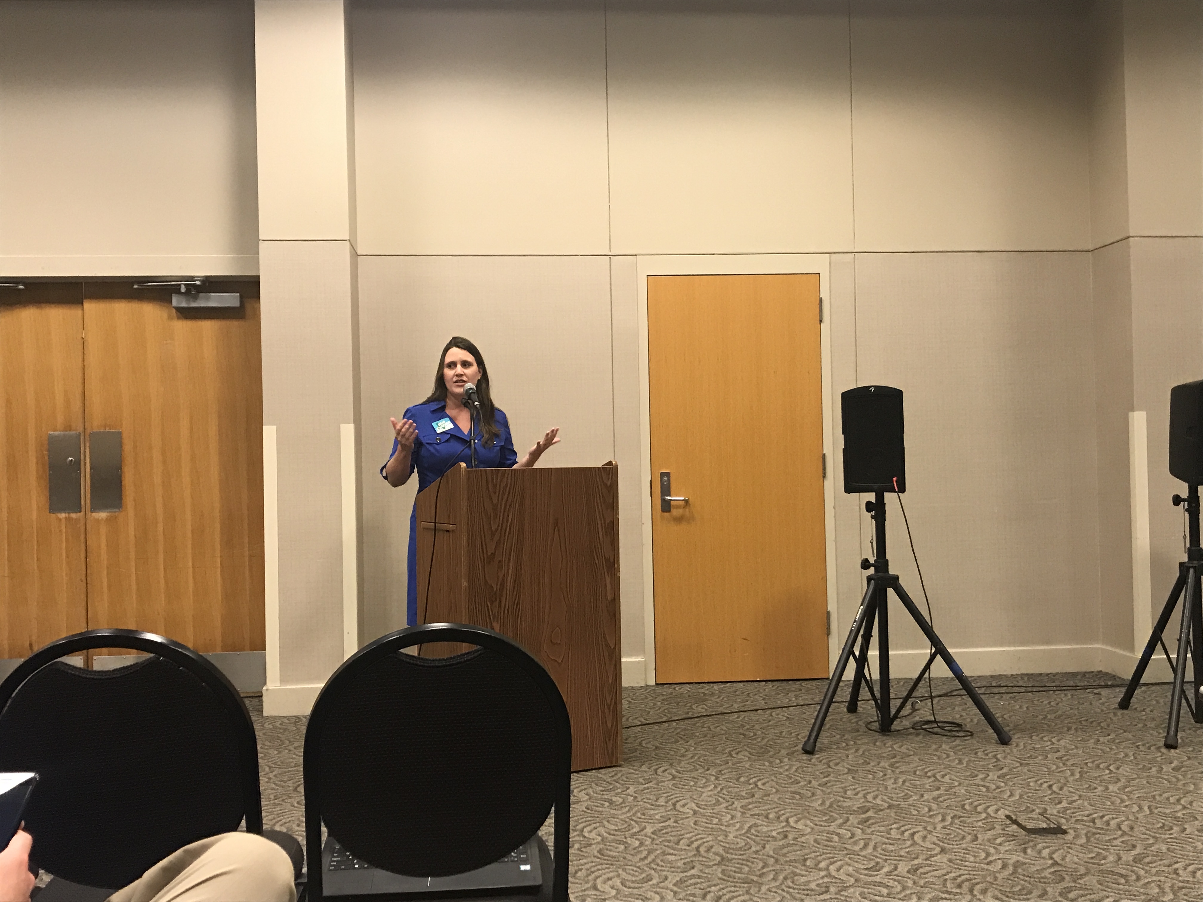Erin Zwiener standing behind a podium talking to audience during a town hall
