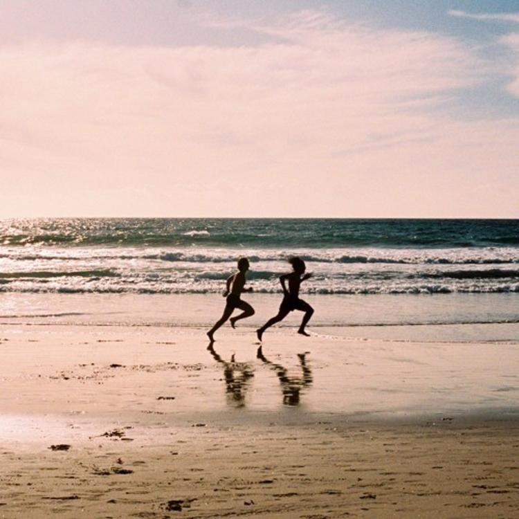 Two people running down the beach