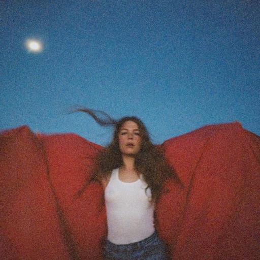 Maggie Rogers holding a red blanket behind her.
