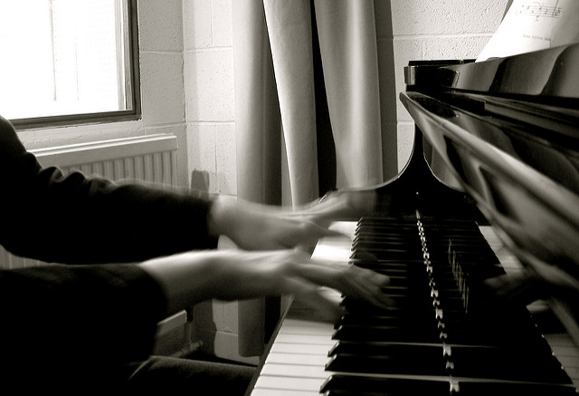 The picture is back and white of two hands playing the piano.