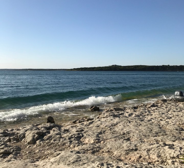 The image features an angled view of Canyon Lake with small waves hitting the rocky shore.