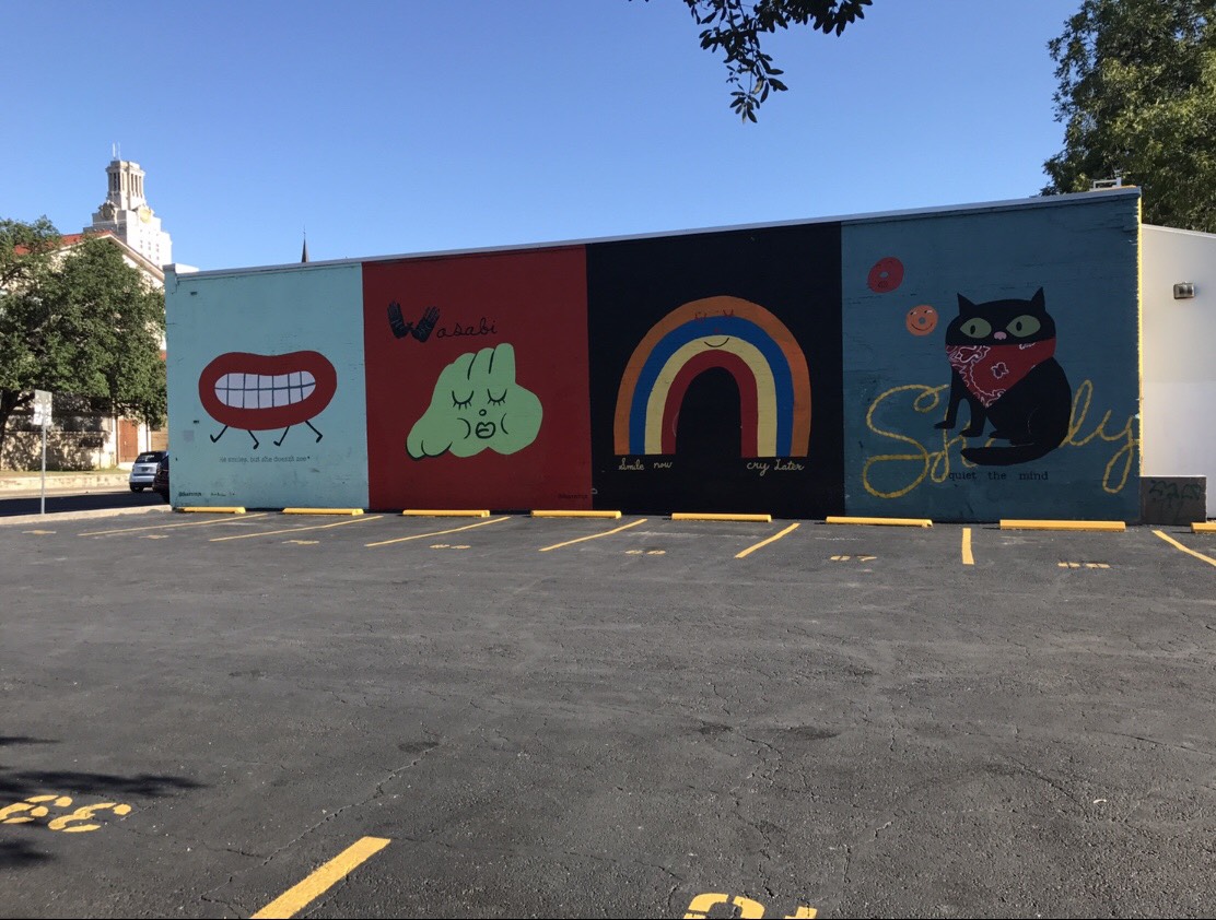 A wall painted with different panels of colorful, simple cartoons.