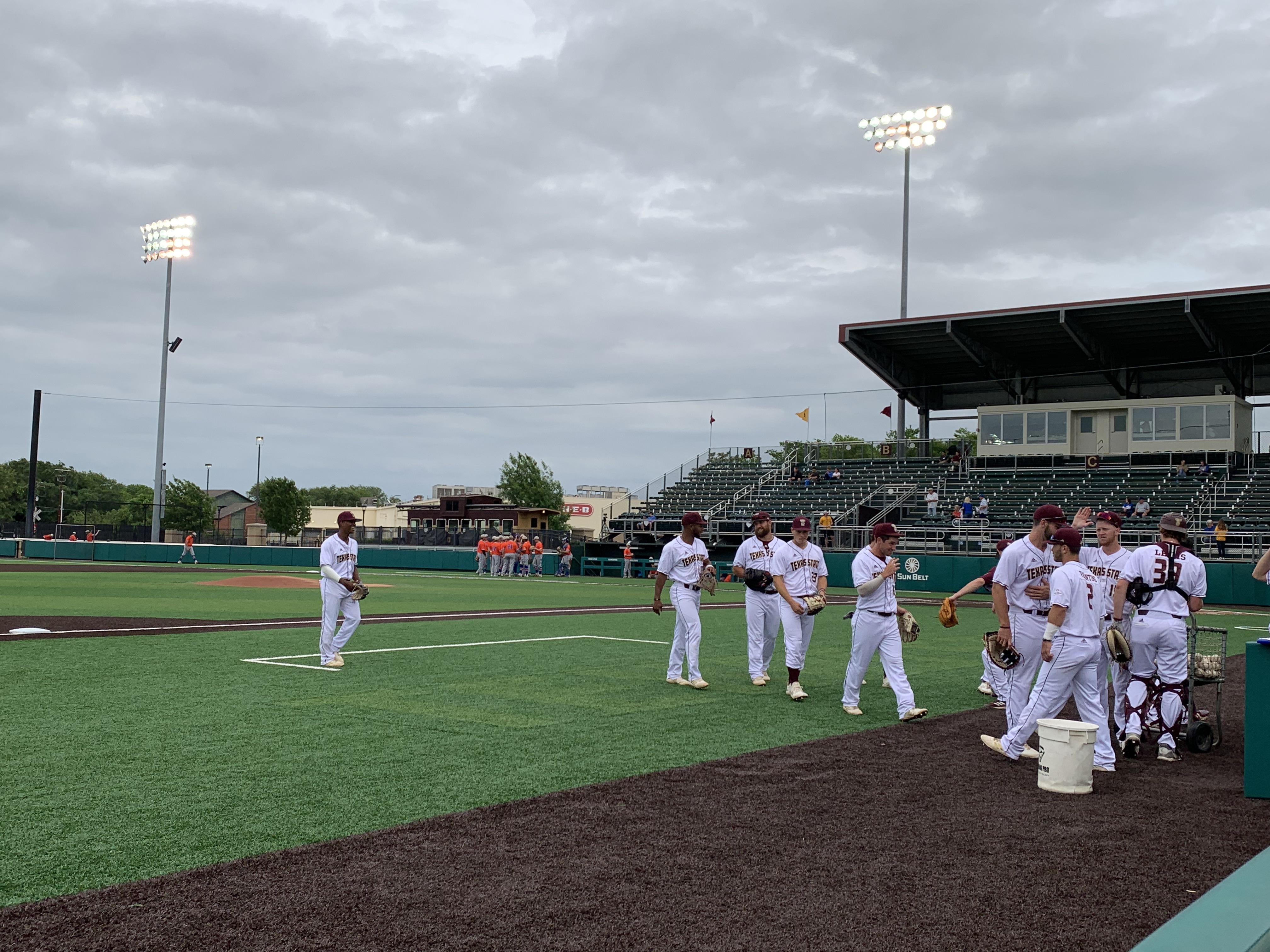 The Texas State baseball team share smiles and high fives in warmups before their matchup with the Houston Baptist Huskies on April 16, 2019.