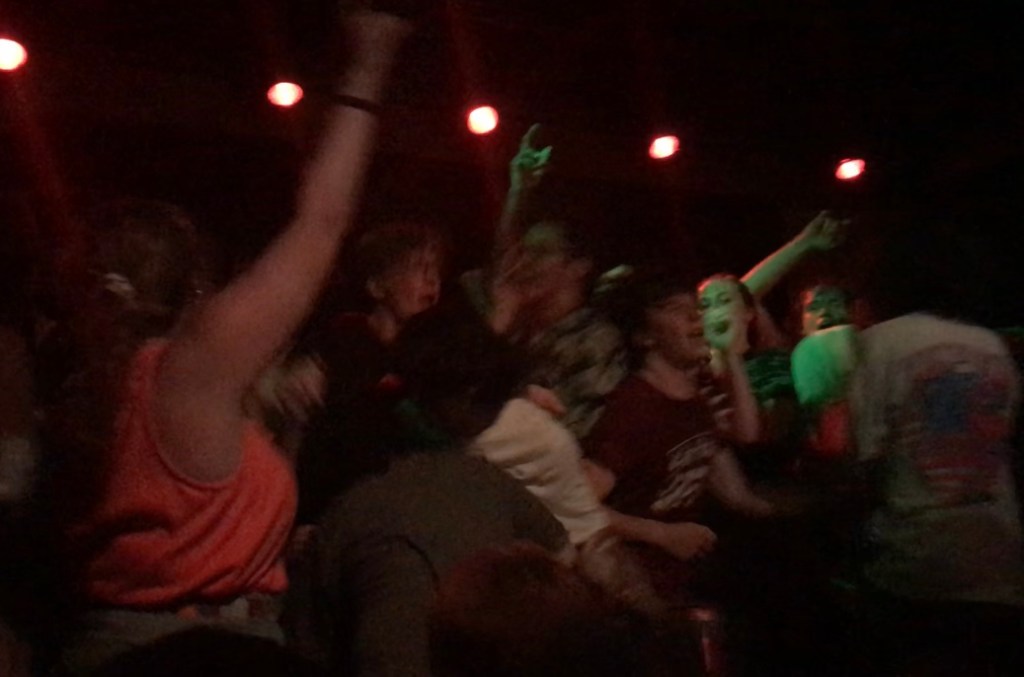 Multiple people on stage dancing and waving their arms in the air.