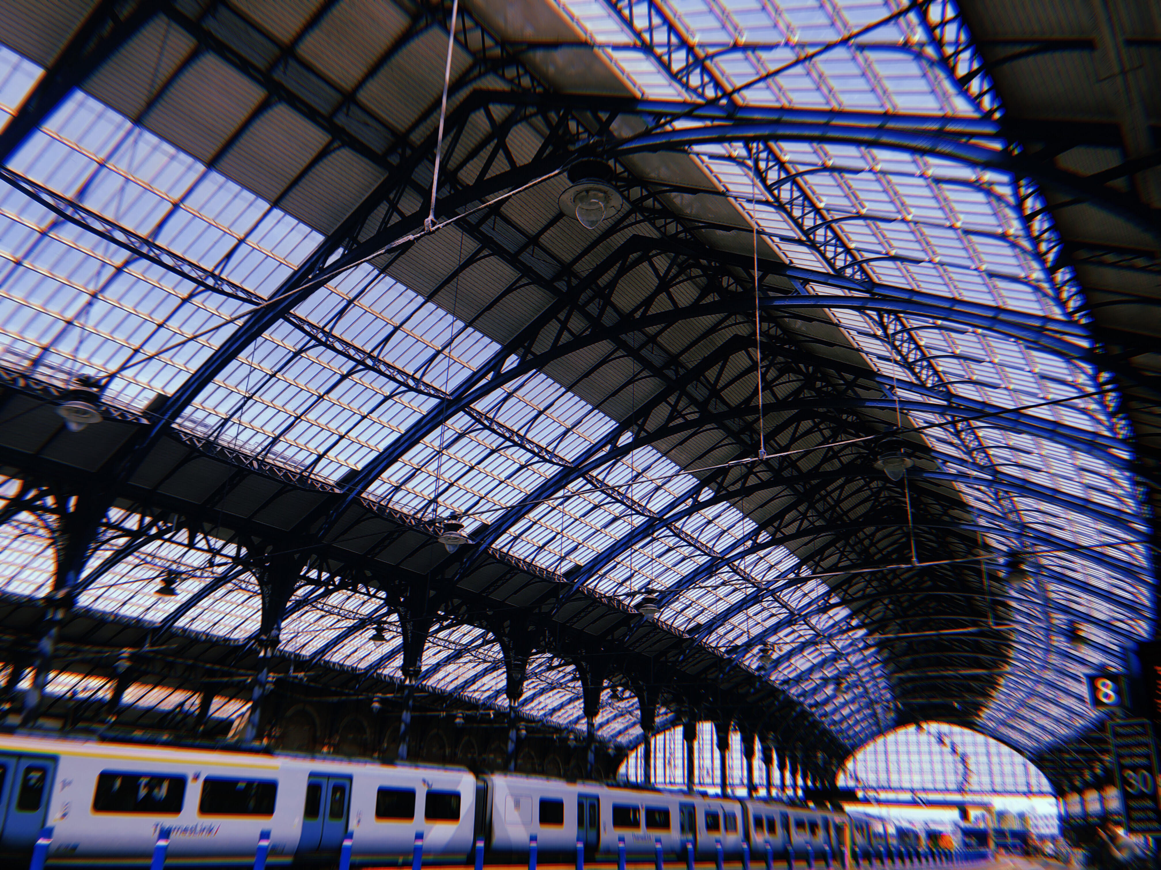 A photo of Brighton Railway Station with bright glass ceilings and a line of train cars.