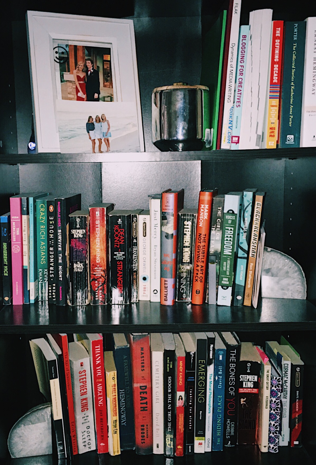 A bookcase featuring multiple books and picture frames