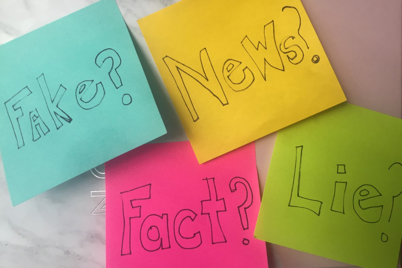 four colorful sticky notes on a marbled background with one reading “Fact?” another “News?” another “Fake?” another “Lies?”