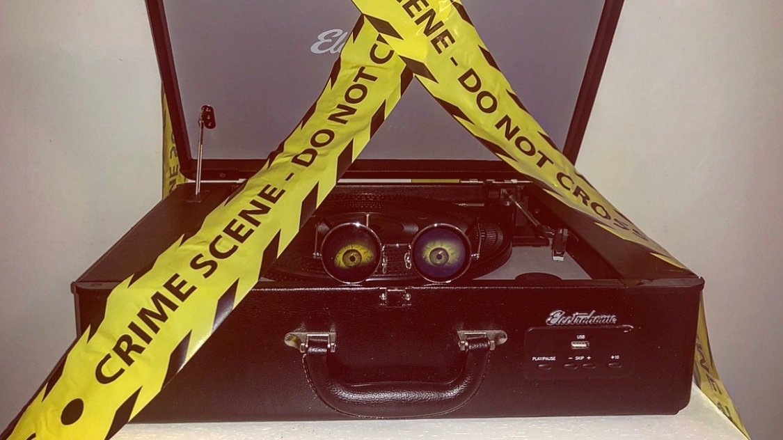 a record player with spooky glasses on and caution tape around it.