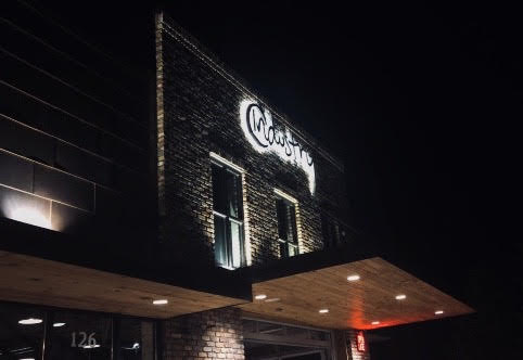 The outside of the restaurant with a lit up sign that says Industry.
