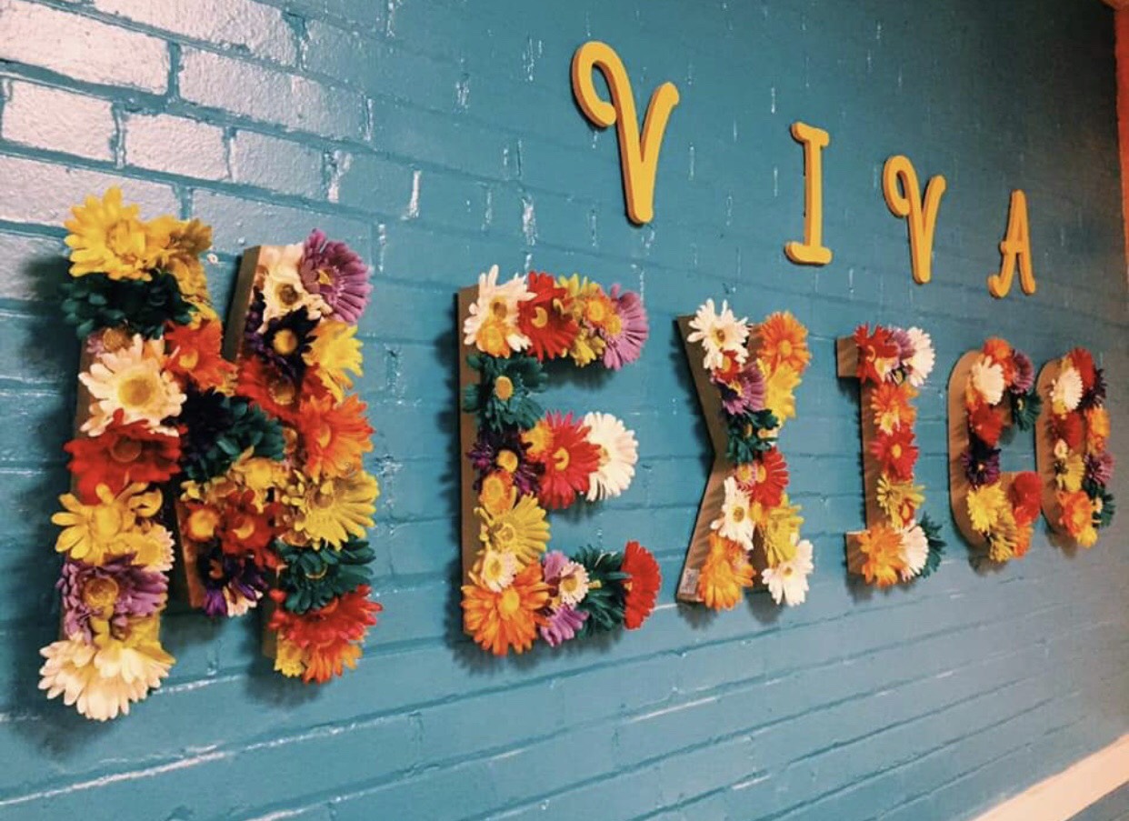 A turquoise wall with “Viva” in yellow and “Mexico” in flowers