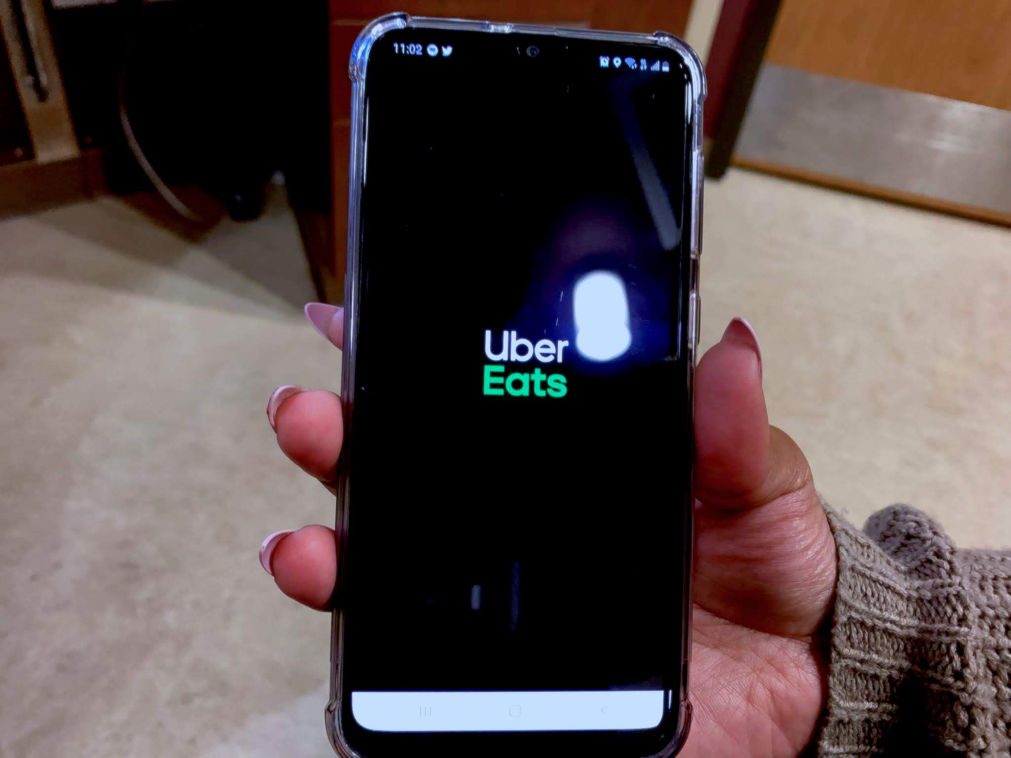 UberEats App cover page on a phone, a black background with Uber in white and Eats in green.