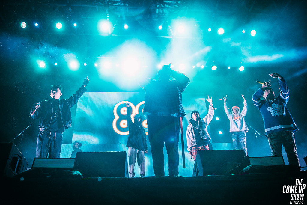 The Group, 88rising, performing on stage at their 88 Degrees and Rising Tour, The Higher Brothers, Rich Brian, and August 08 are seen on stage with an 88 logo in the background.