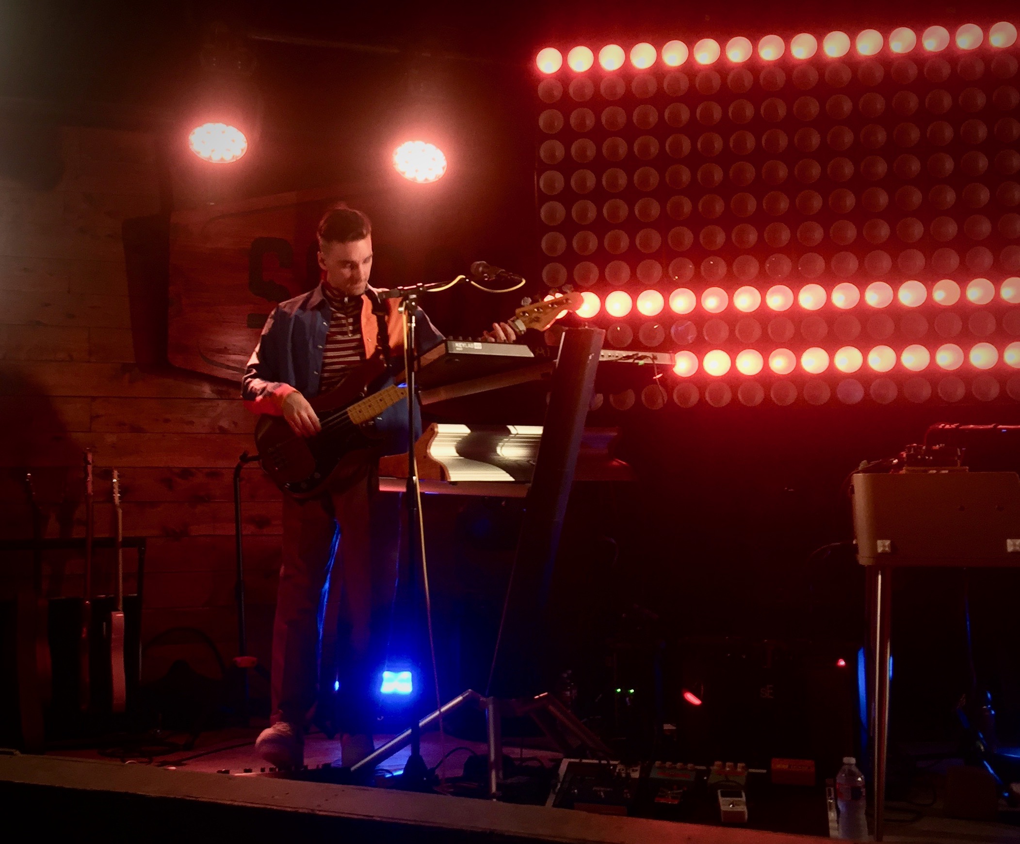 A man playing bass on a stage with red lights shining on him