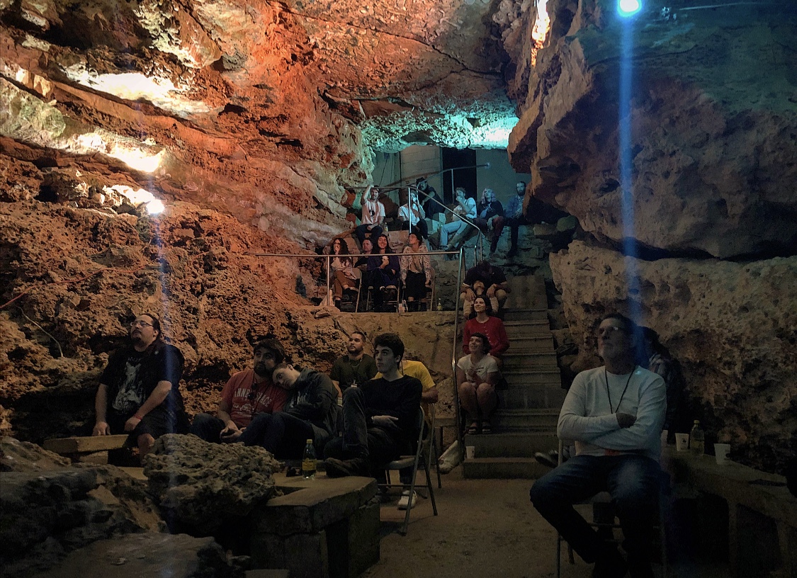 An audience watching a movie screening inside a cave.