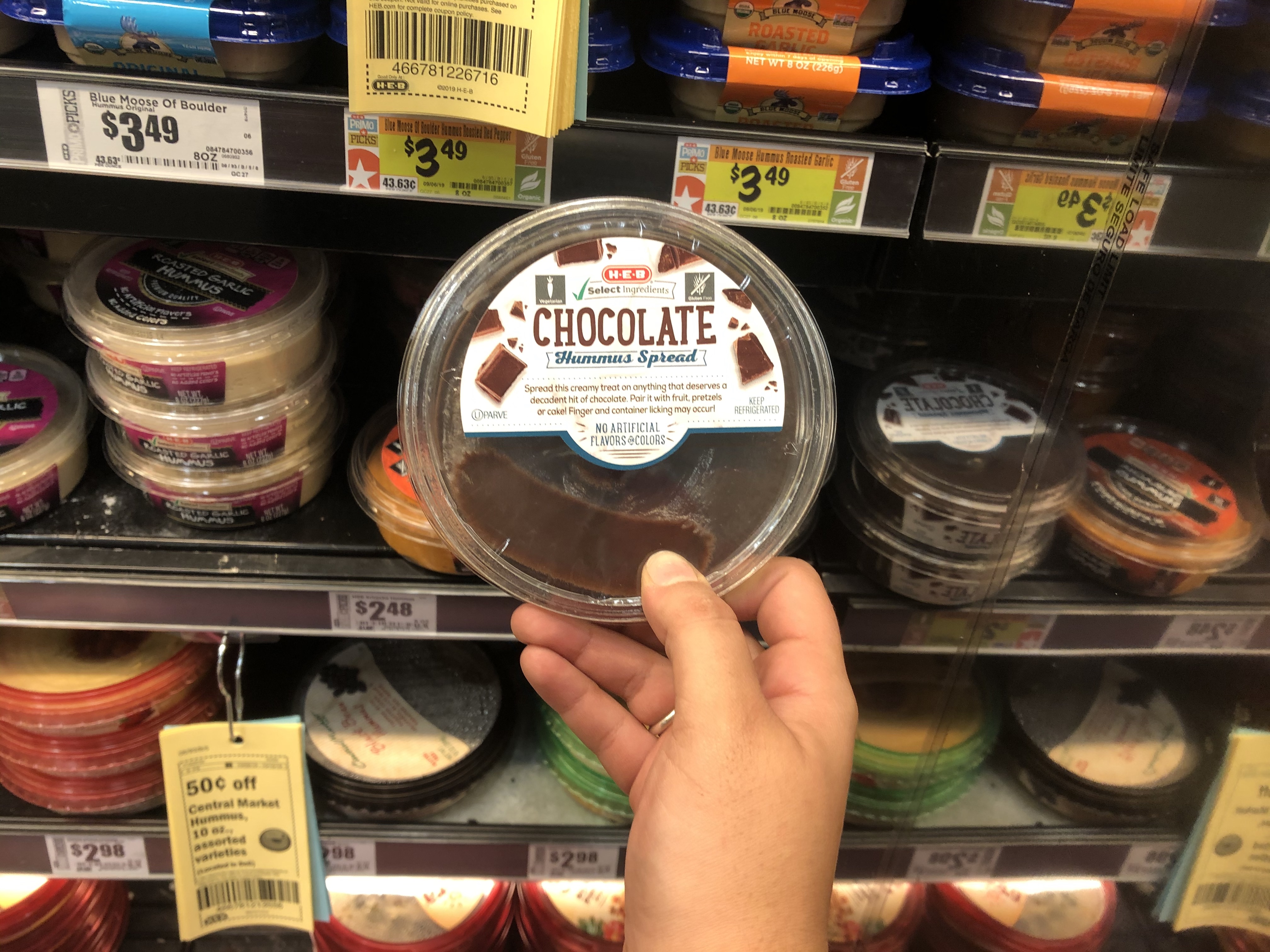 This is a picture of me holding a thing of unopened chocolate hummus at HEB in the Meal Simple section.