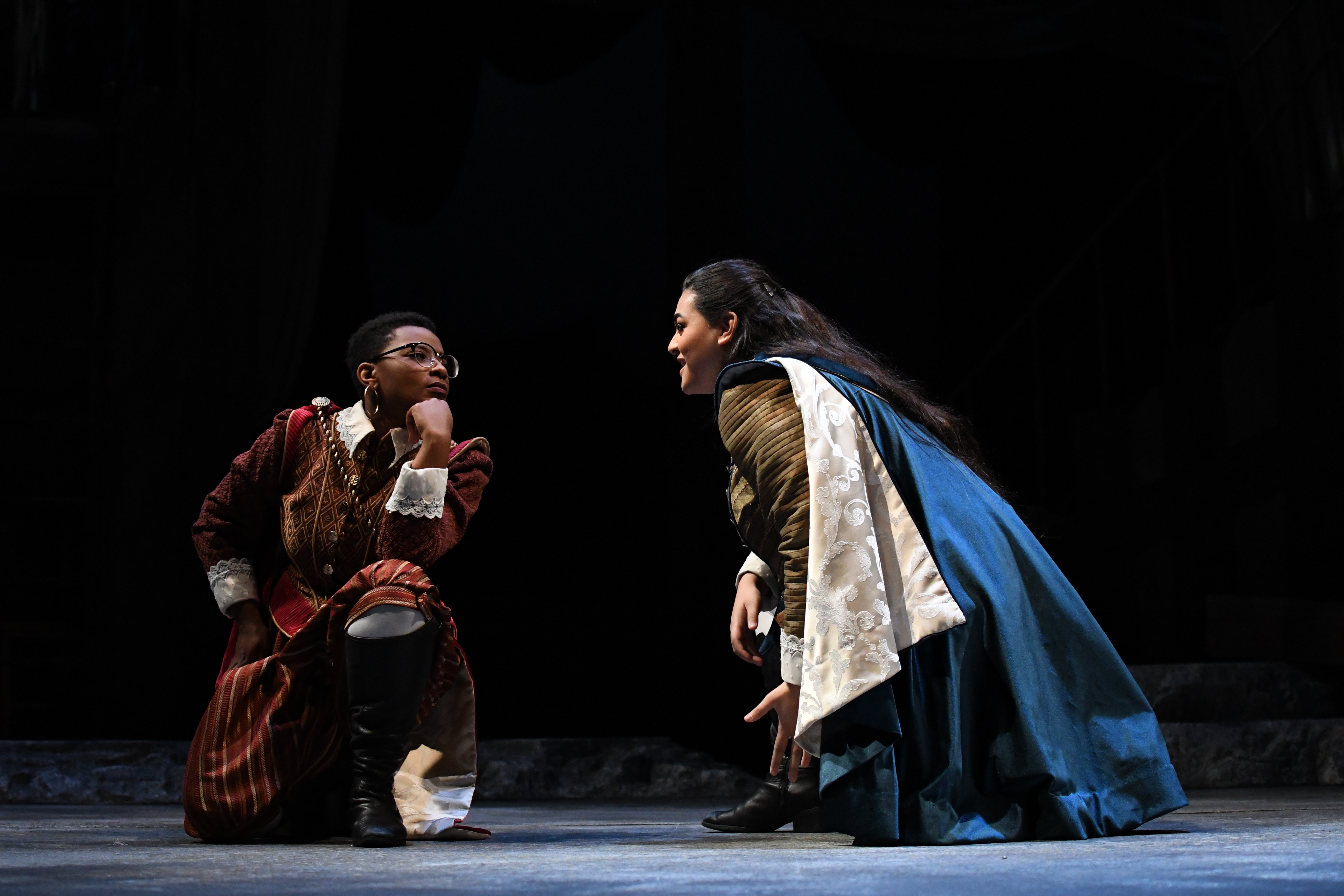 Two women in period costumes kneeling on the floor.