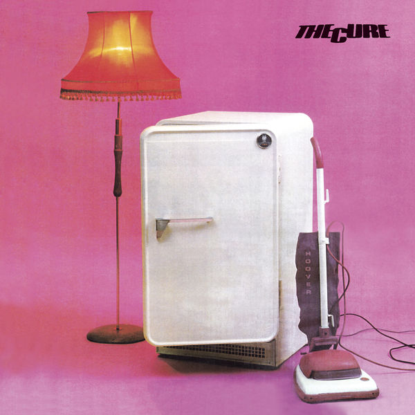 An album cover with a pink backdrop and a fridge, lamp and vacuum