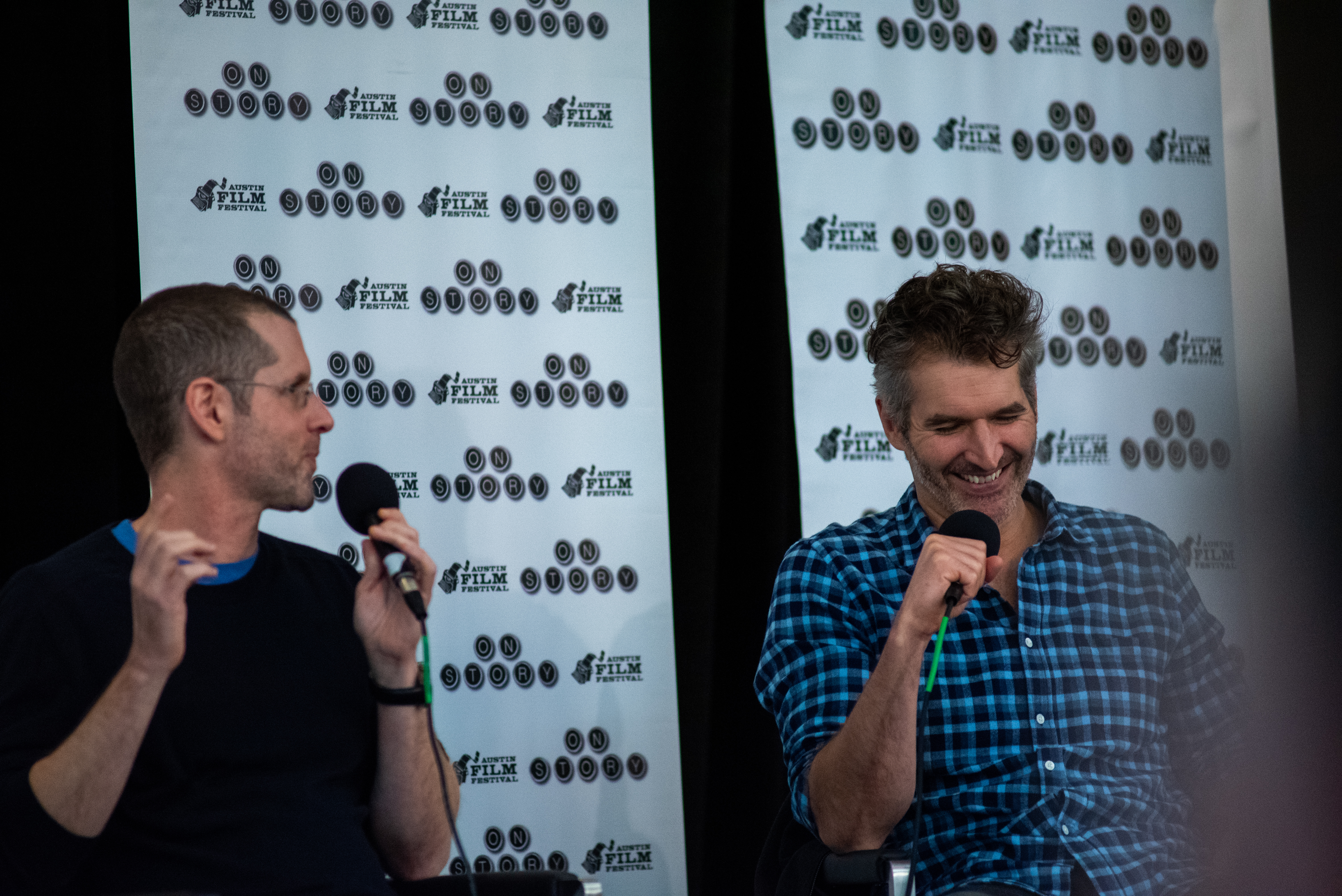 Two men holding microphone.