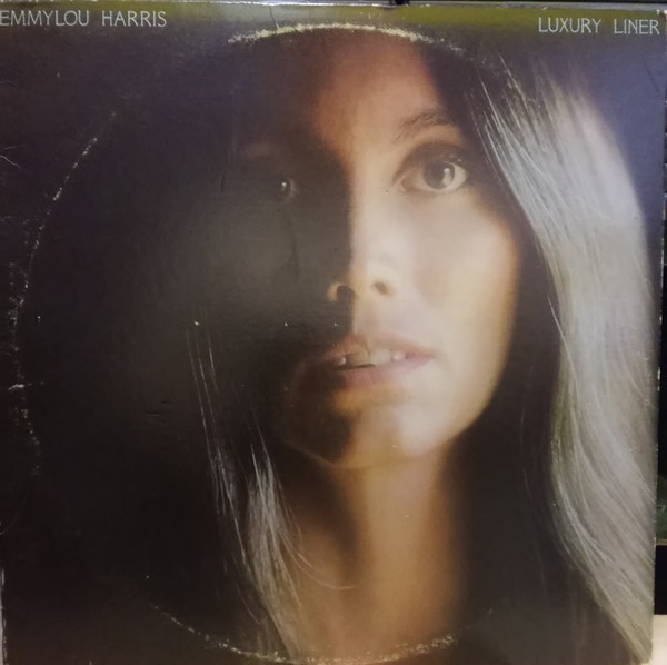 The face of the artist, Emmylou Harris, is the predominant image in this artwork. The name of the artist is in the top left of the image, the album title in the top right