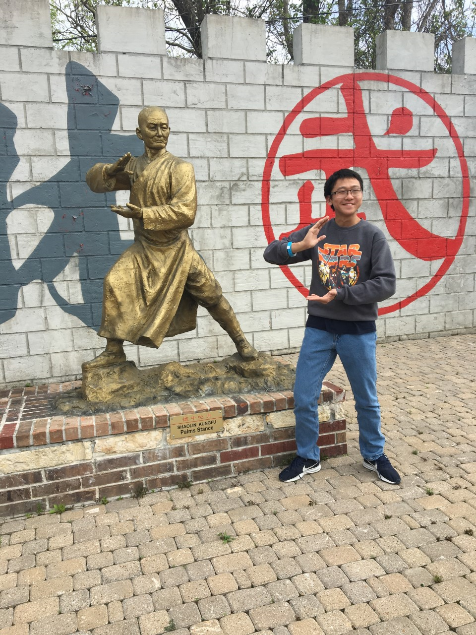 A visitor poses with a Shaolin monk statue. 