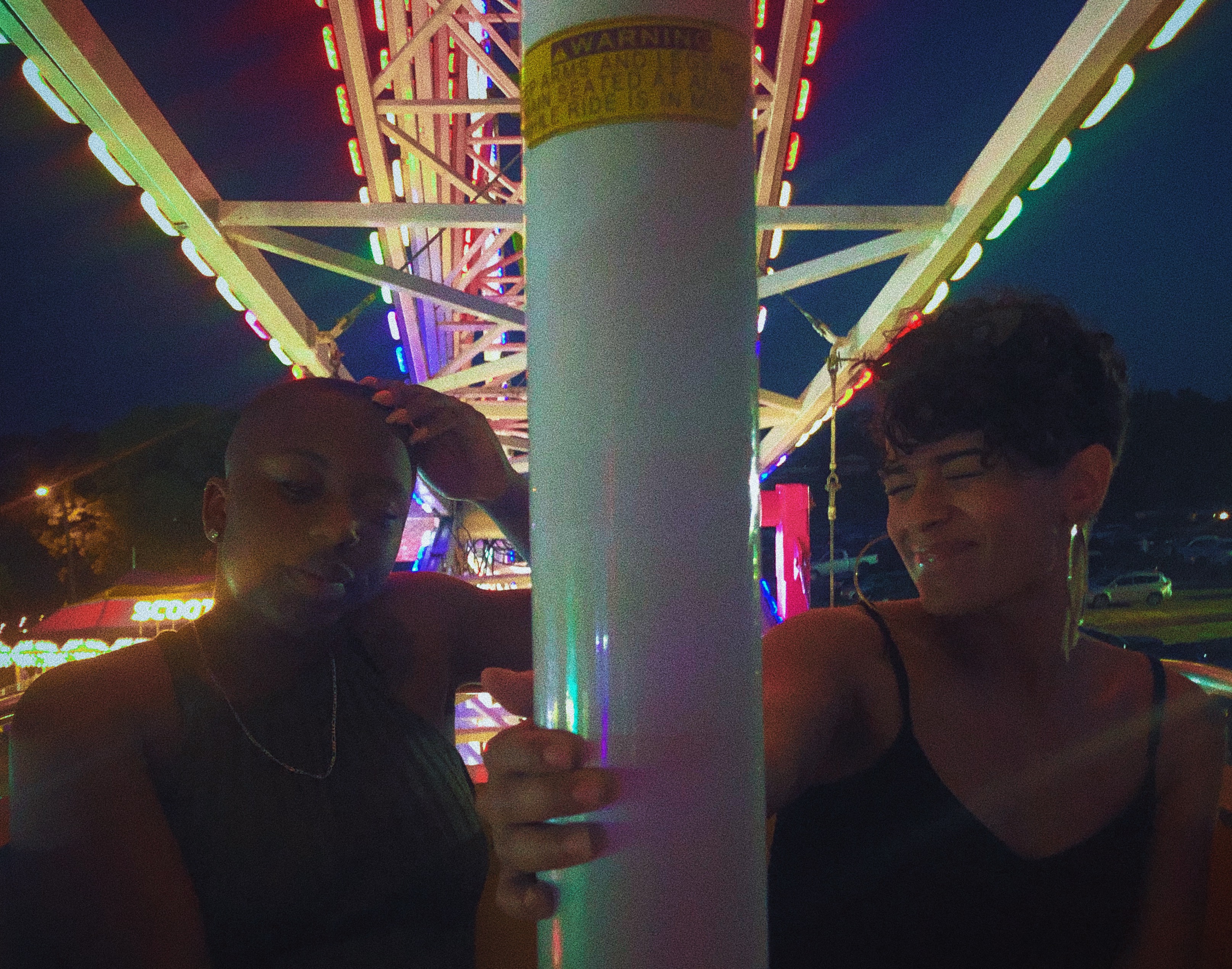 Two friends on a ferris wheel at an amusement park.