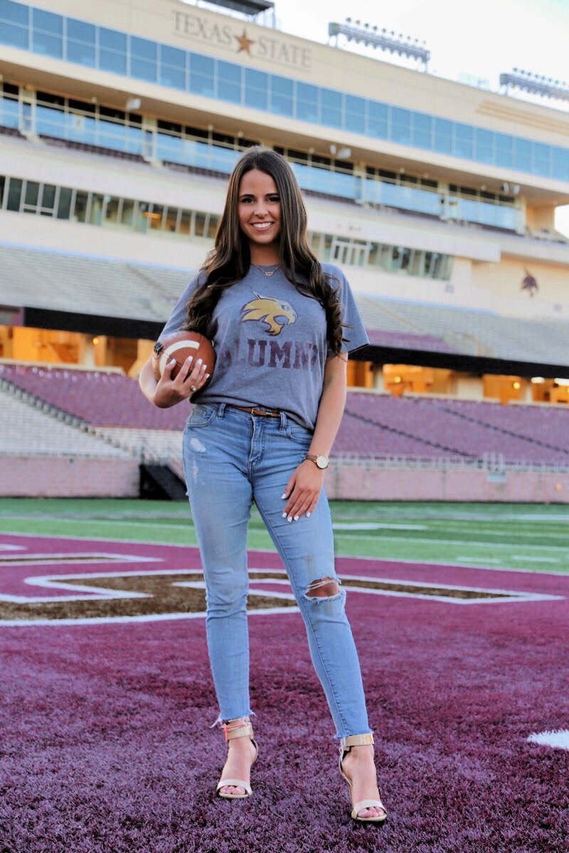 Blocker standing in the endzone holding a football in her right arm, with the home stands in the background.