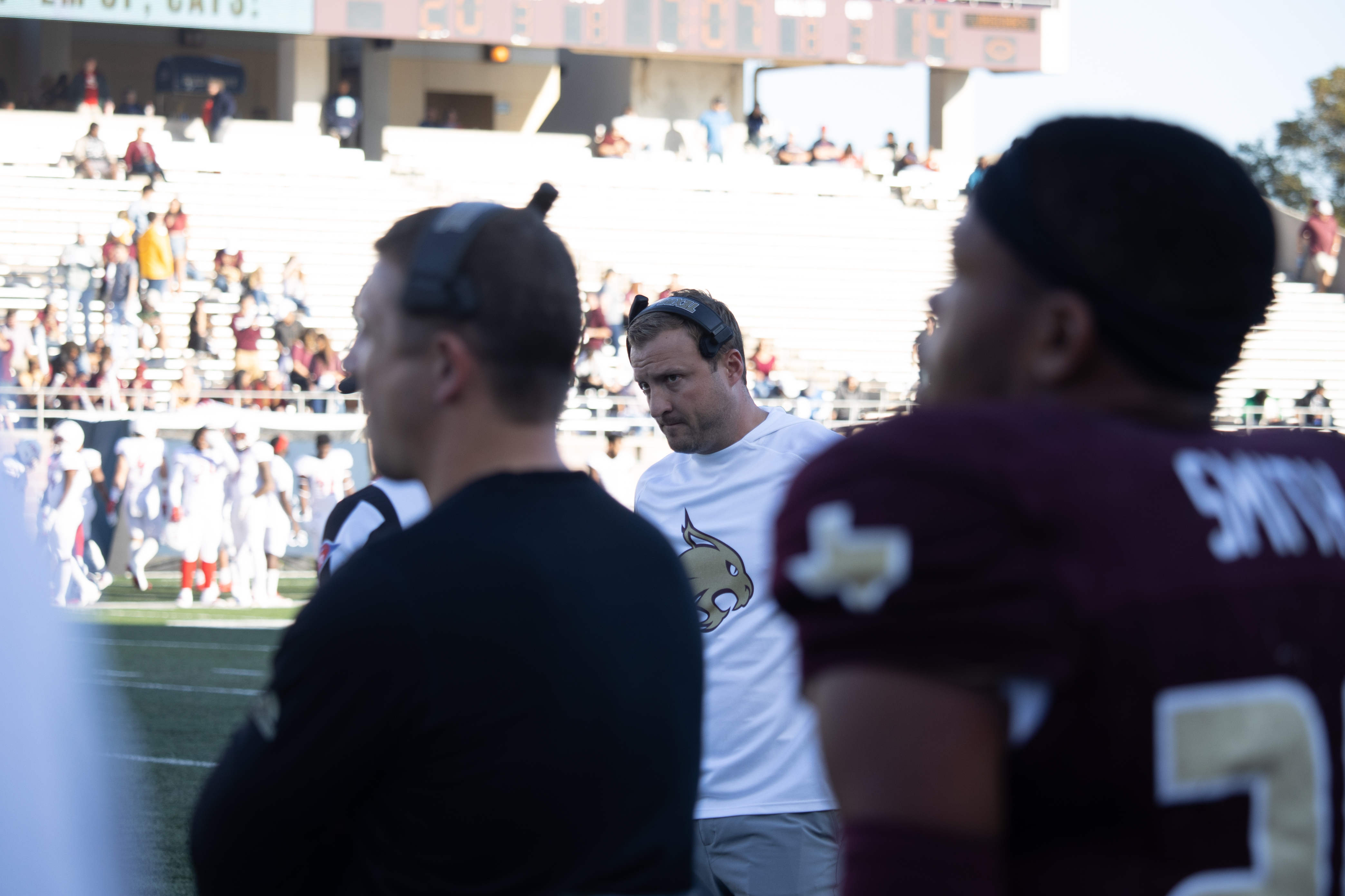 Jake Spavital is between a football player and a coach in the photograph on the sideline.