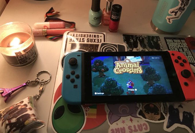 Image of Nintendo Switch on desk, surrounded by different objects with "Animal Crossing" on screen.