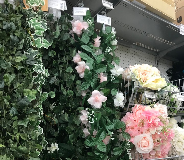 Image of faux pink roses on green vine surrounded by other fake flowers at Michaels.