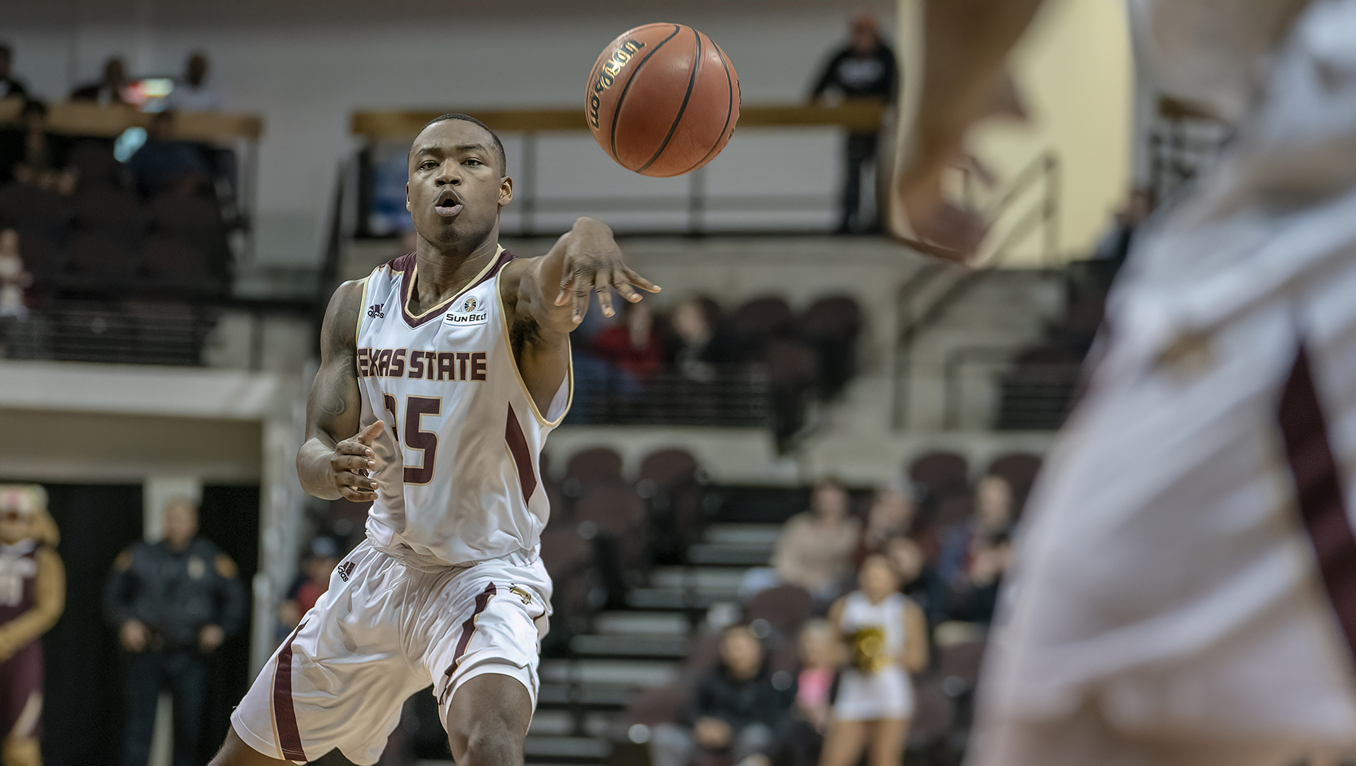 Jaylen Shead in a white and maroon Texas State jersey passes the ball to a teammate during a basketball game at Strahan Arena in San Marcos, Texas.