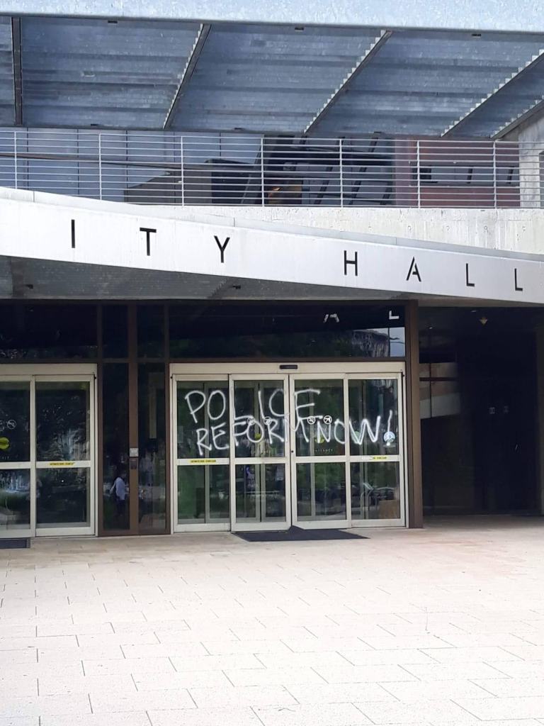 Police Reform Now! Spray painted in white on the windows of Austin’s City Hall
