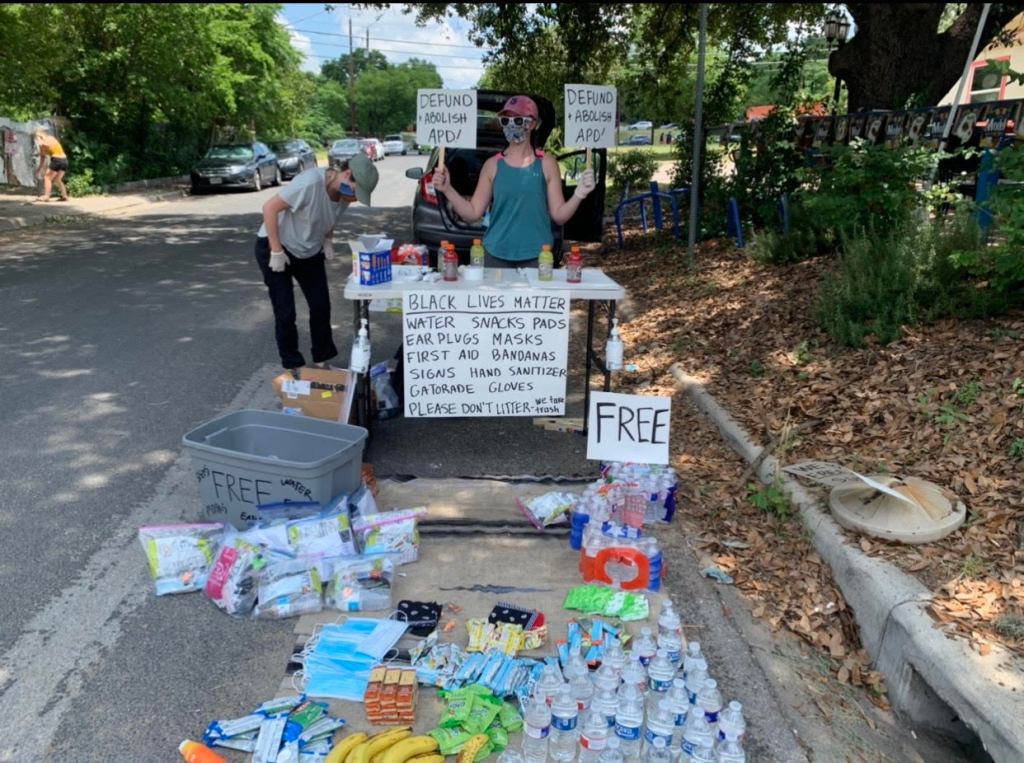 Photo of a stand with free water, snacks, and sunscreen at the protest