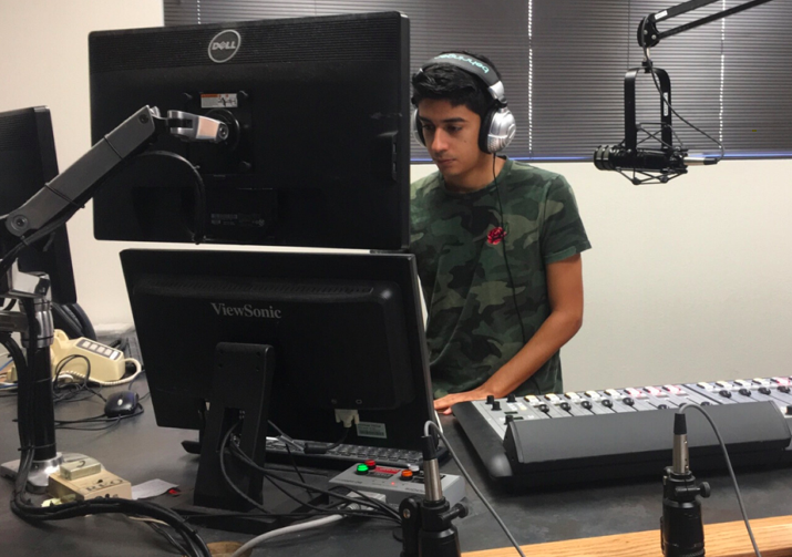 Man in front of the computer with headphones and microphones.