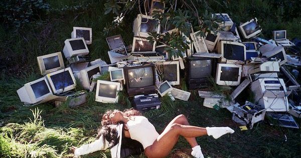 Album art of "CTRL" with SZA in a field of busted computers and greenery, bathing in the sunlit.