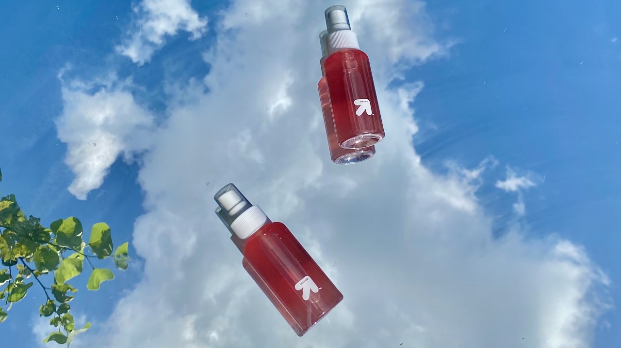 Image of two spray bottles filled with rosewater with the sky in the background