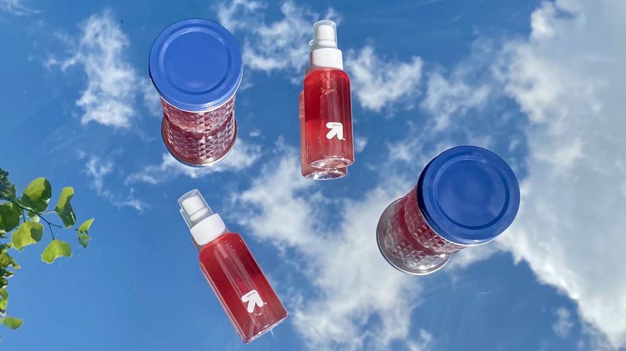 Image of two spray bottles and two mason jars filled with rosewater with the sky in the background