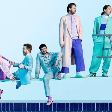 A picture of six people posing on a diving board, dresses in pastel blues and purples.