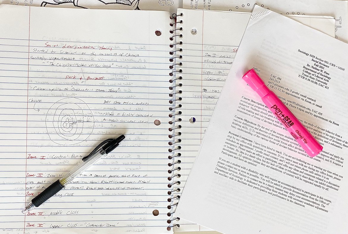 A notebook is spread across the table with a Sociology syllabus on top on the notebook. On top of the papers is a pen and a pink highlighter.