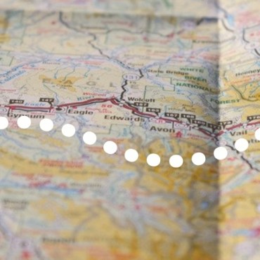 The background of the image features a paper map, with two red hearts in different parts of the map connected by a white dotted line.