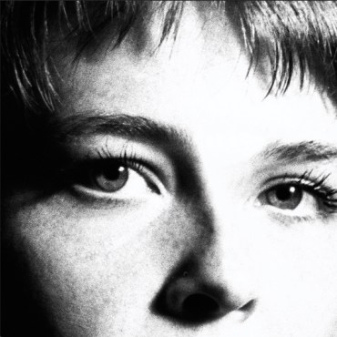 A close up black and white photo of the center of Maggie Rogers’ face. Shown are both of her eyes, nose, and forehead. A soft shadow is forming on the right side of her face.