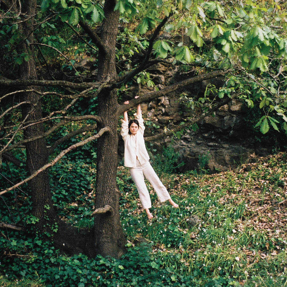 pictured is Tori Zietch, Maple Glider, hanging onto a tree dressed in all white.