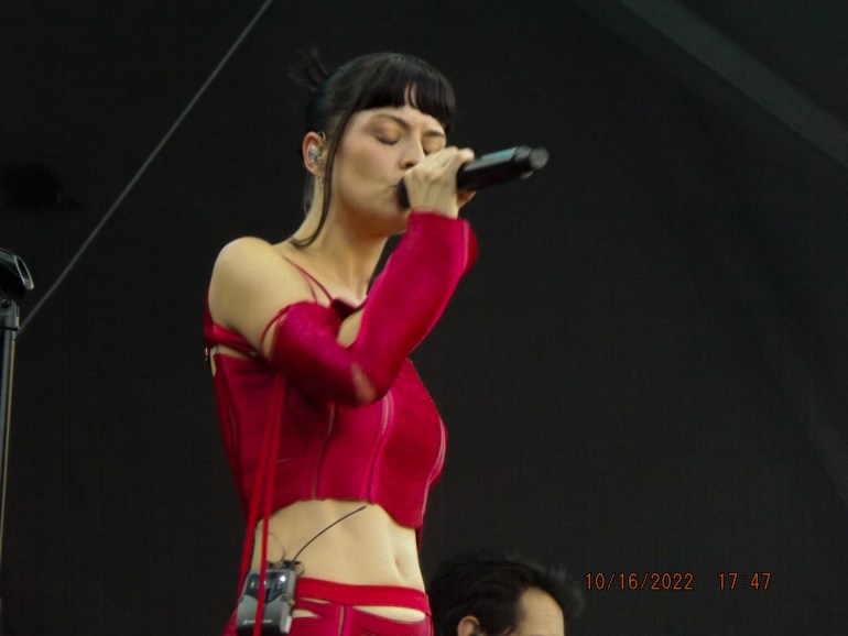 Zardoya in red two-piece with microphone.