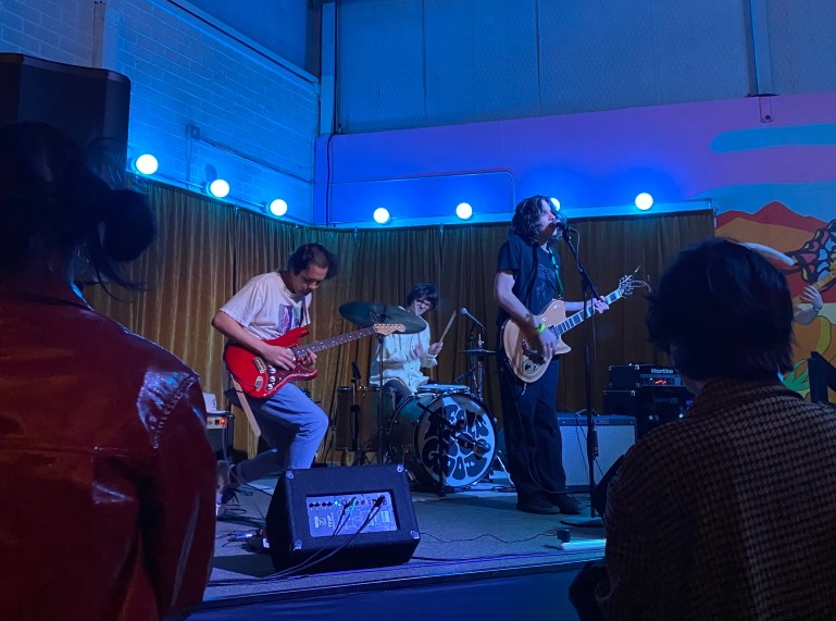 Four band members performing on stage in blue lighting