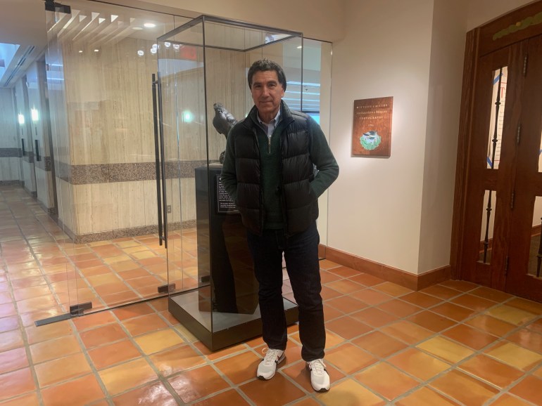 Hector, the Music Curator of the Wittliff Collections, in front of a glass stand and smiling