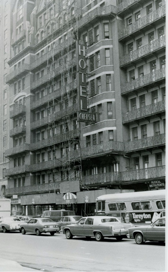 : The photo shows an older Chelsea Hotel with a sign displaying the name of the building, “Hotel Chelsea”.  