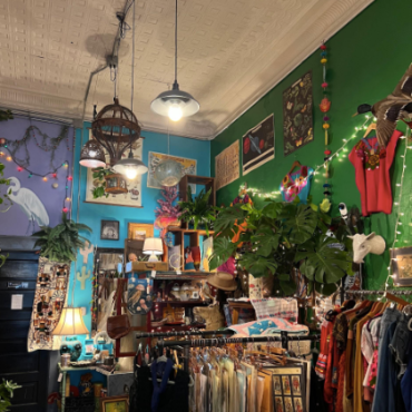 Image of a shop with blue and green walls, lanterns hanging from the ceiling, and racks of clothing.